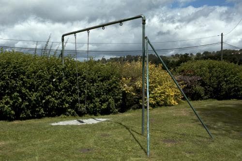 Une balançoire usée dans le coin d'un jardin et au bord d'une haie sur fond de ciel contrasté. Dans la Creuse en France