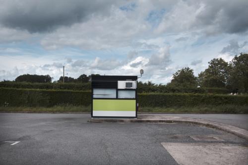 Un kiosque fermé sur un parking déserté sur fond de ciel contrasté. Dans la Creuse en France