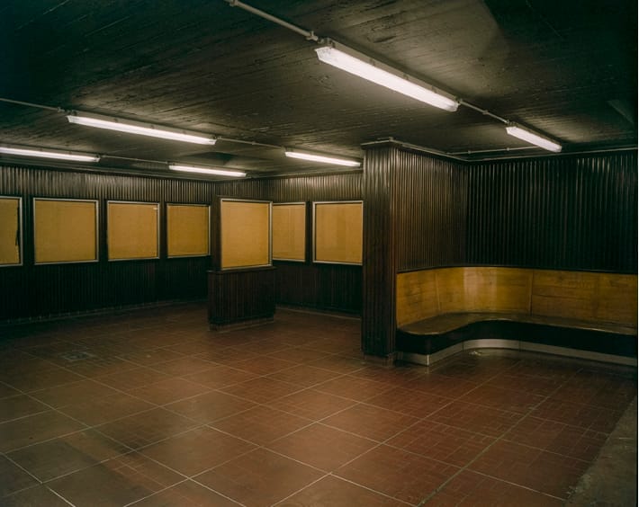 Gare du congrès à Bruxelles, la salle des horaires en bois abandonnées, des néons au plafond et un banc en bois dans la partie sale 'attente, photographie argentique moyen format Plauble W67