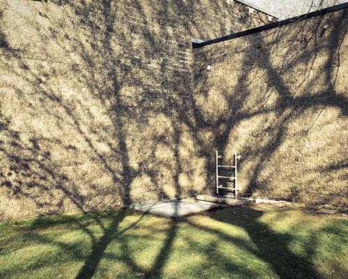 Une trape escalier de secours dans le coin d'un vieux bâtiments de l'hôpital Brugmann à Bruxelles, aevc des ombres projetées de branches d'arbres et un soleil d'automne, photographie argentique moyen format Plauble W67